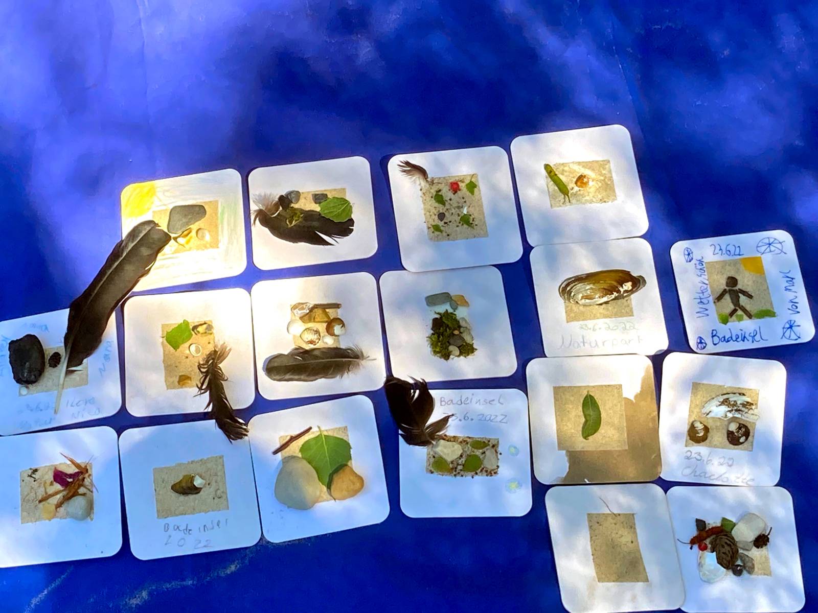 Kleine Kunstwerke zum Mitnehmen: Naturmaterialien sind auf quadratische Pappdeckel geklebt.